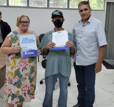 Dona Laura Oliveira Martins (Presidente da Associação de Produtores da Comunidade Paredão) e Francisco Serafim de Barros (Presidente do INTERMAT) ladeiam morador beneficiado
